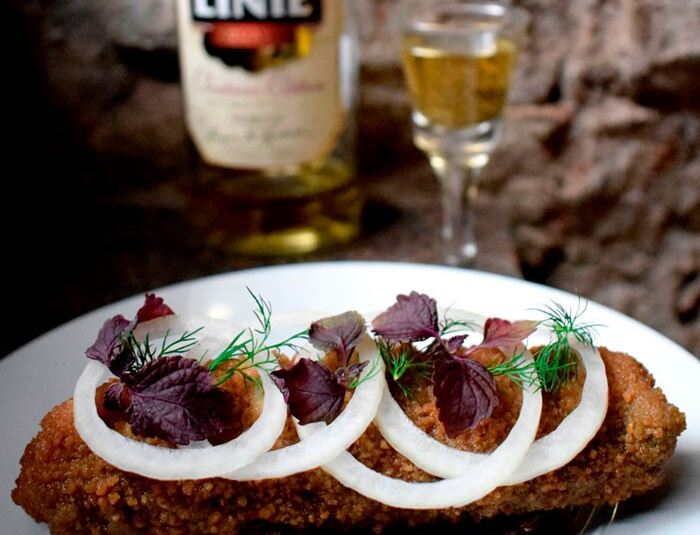 Dansk frokostret bestående af stegte sild med rugbrød og toppet med løgringe og dild.