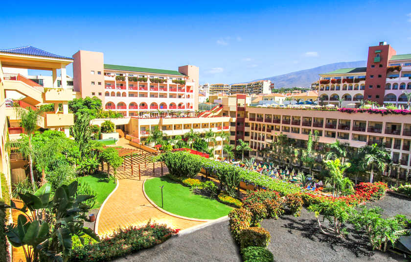 en udsigt over det firestjernede Hotel Best Jacaranda i Costa Adeje på Tenerife, med de karakteristiske lyserøde bygninger og frodige grønne omgivelse