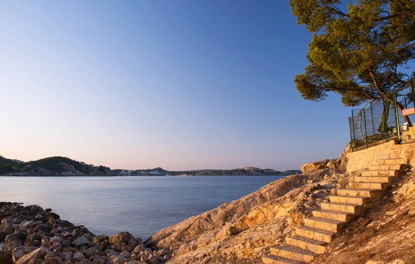 Kystlinje ved Paguera på det sydvestlige Mallorca i Spanien, hvor klipper møder det rolige Middelhav ved solopgang.