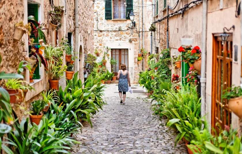 Brostensbelagt gade flankeret af gamle stenhuse i den maleriske bjerglandsby Valldemossa på den spanske ø Mallorca.