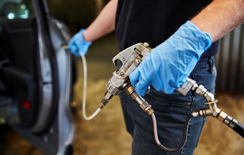 PAVA medarbejder i gang med at spray bil med rustbeskyttelse